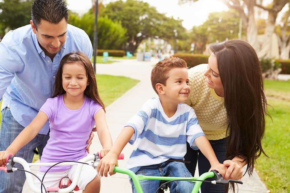 Family riding bikes together in park near San Fernando Valley Collection